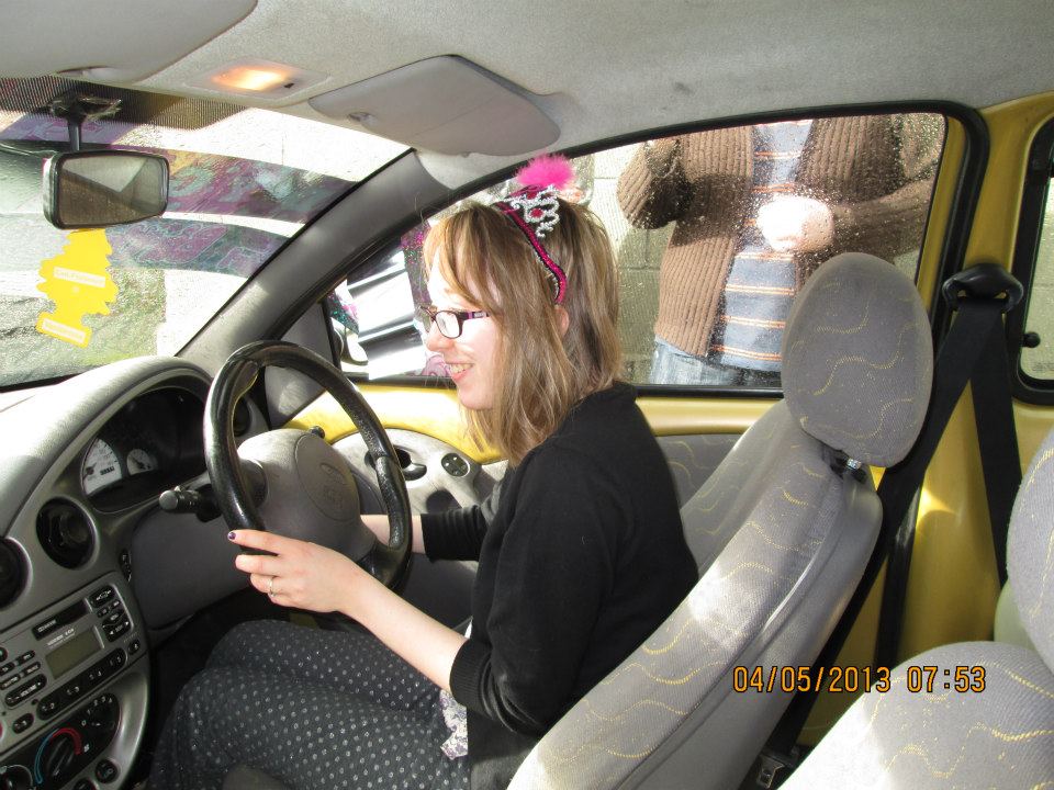 Me sitting in my first car. I'm smiling and wearing pyjamas and a cheap birthday tiara.