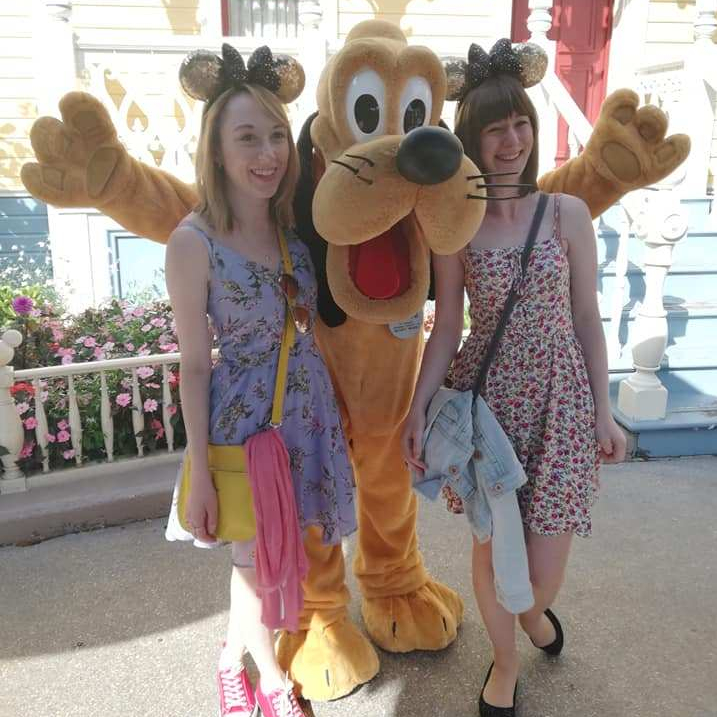 Photo of me and Lillie stood either side of Pluto on our trip to Disneyland.
