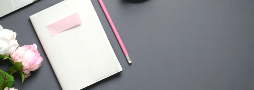 White journal on grey flatlay with pink pencil