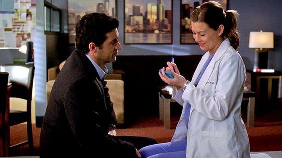 Screenshot from Grey's Anatomy - Meredith and Derek get married on a Post-It. Meredith smiles as she signs the Post-It while Derek watches.