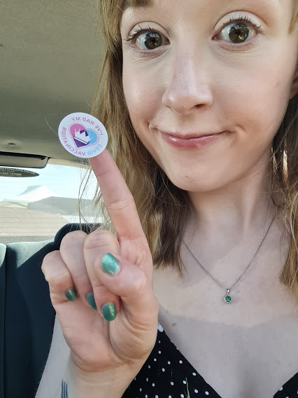 A picture of me sat in my car post vaccination. I have a sticker on my finger that says "I've had my Covid vaccination."