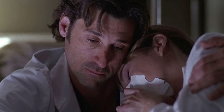 Derek comforts Meredith, who is blowing into a paper bag.