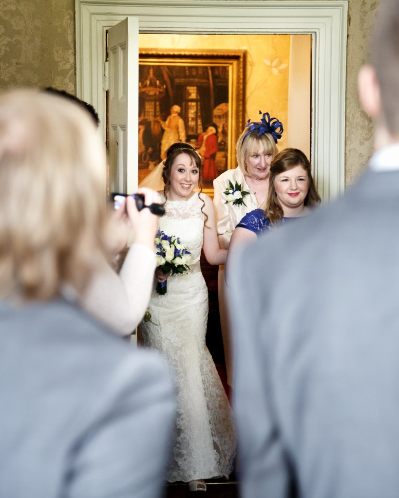 My Mum walking me down the aisle on my wedding day, led by my sister-in-law and bridesmaid. Stacey. The photo is taken over the shoulder of Liam and his best man, Josh